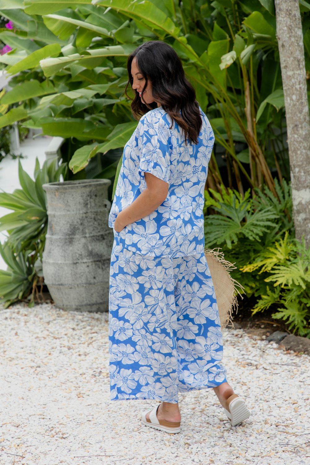 Woman in a blue and white floral Relaxed Fit Summer Pants and Kaftan Top set standing in a resort garden setting