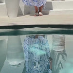 lady wearing maxi kaftan in sea blue and white flower print design while enjoying pool surrounds.