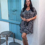 A woman posing in a leopard print short kaftan dress in front of a cocktail bar in Thailand on holidays