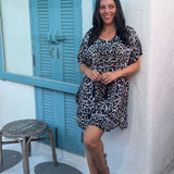 A woman posing in a leopard print short kaftan dress in front of a cocktail bar in Thailand on holidays
