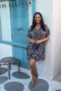 A woman posing in a leopard print short kaftan dress in front of a cocktail bar in Thailand on holidays