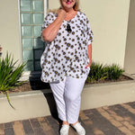Jacqui from New Style Chapters wearing the White Daisy kaftan top with black and yellow daisies, styled with white pants.