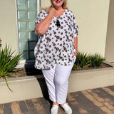 Jacqui from New Style Chapters wearing the White Daisy kaftan top with black and yellow daisies, styled with white pants.
