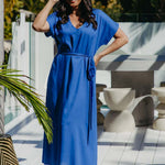 Front view of the Lagoon Blue long kaftan dress styled with its matching waist belt and flat sandals.