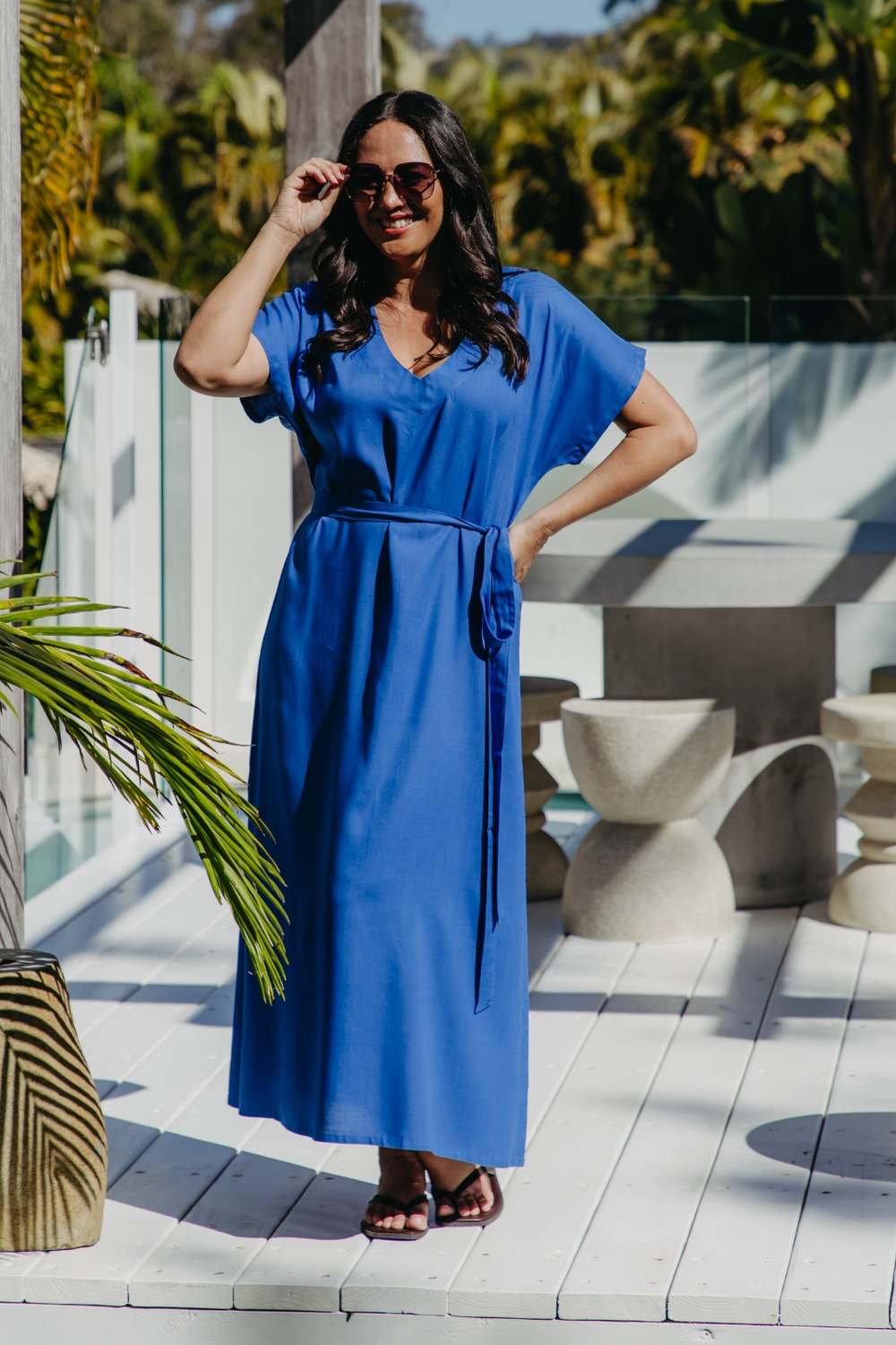 Front view of the Lagoon Blue long kaftan dress styled with its matching waist belt and flat sandals.
