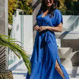Lagoon Blue long kaftan dress with matching belt, showing the side split as the model steps forward on a sunny deck.