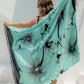 Woman poolside holding a mint green Hawaiian sarong with black hibiscus flower details 