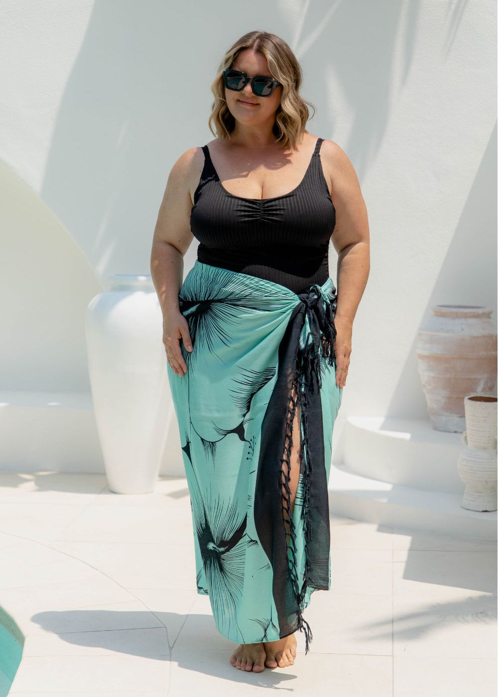 Woman wearing a large beach sarong in mint green and black Hawaiian floral design