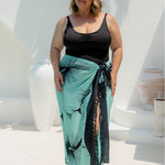 Woman wearing a large beach sarong in mint green and black Hawaiian floral design
