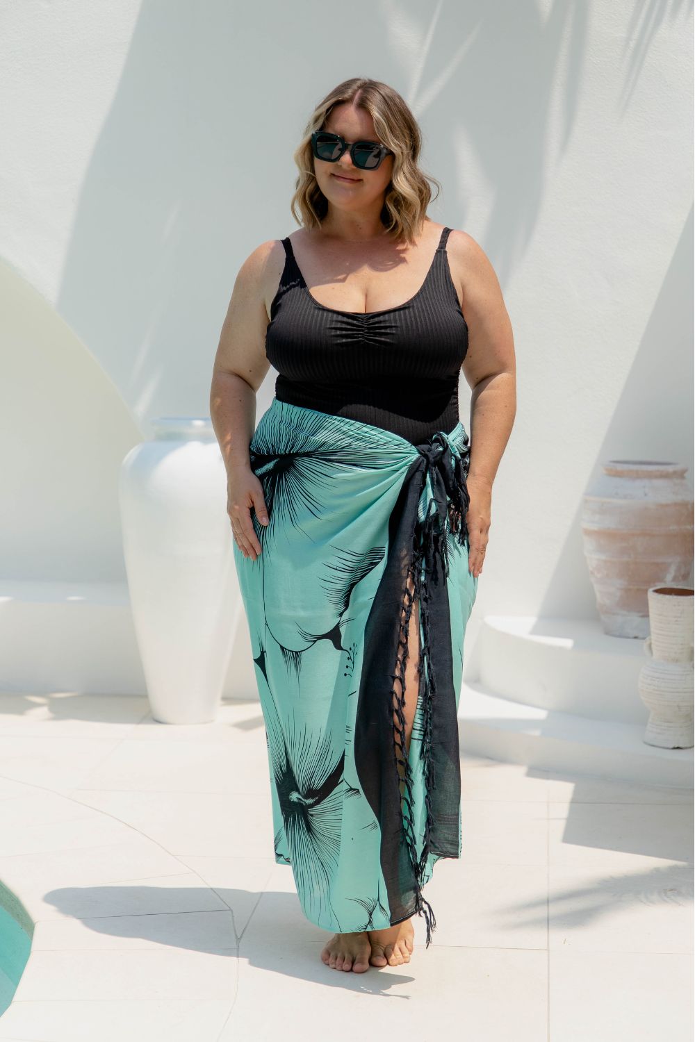 Woman wearing a large beach sarong in mint green and black Hawaiian floral design