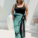 Woman wearing a large beach sarong in mint green and black Hawaiian floral design