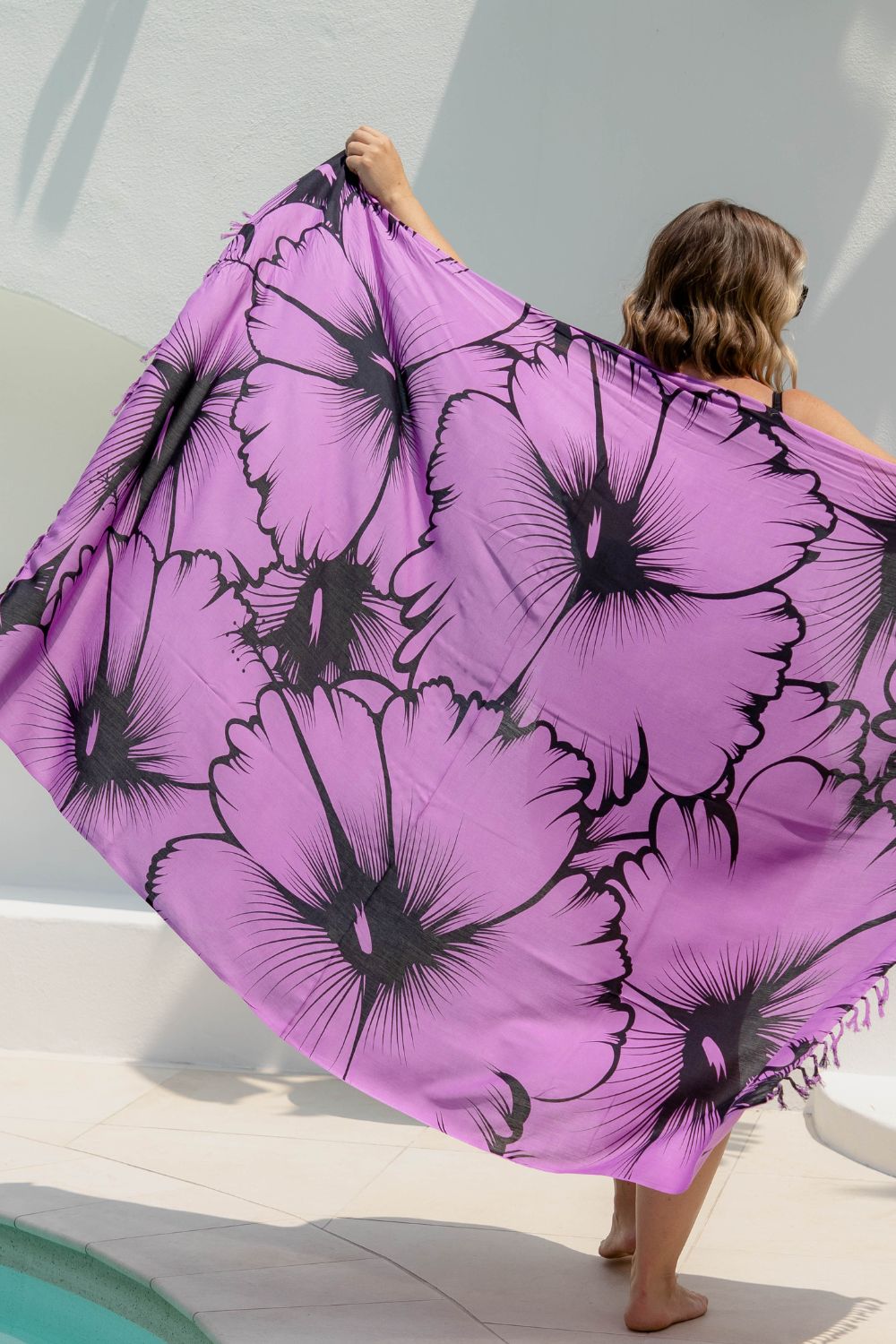 Person holding a large purple Hawaiian sarong with black floral print