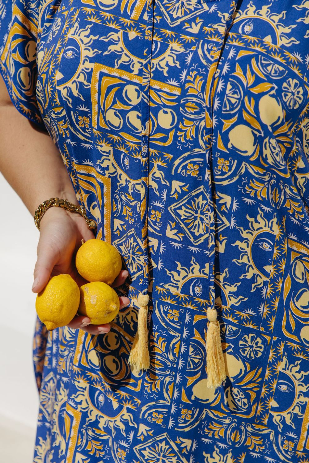 Person wearing a blue and yellow patterned dress holding lemons - the limoncello print