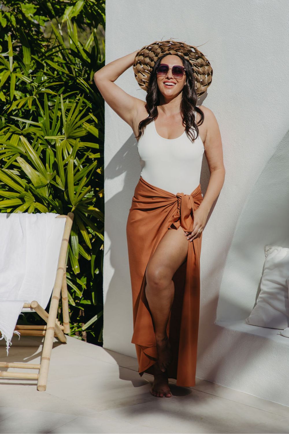 Alisha wearing L sarong in Mocha Mousse, front-on with sun hat, enjoying a sunny poolside moment in summer style