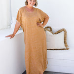 Amanda wearing ML Caramel Scatter dress, front-facing on a sunlit balcony beside a bench with cushions
