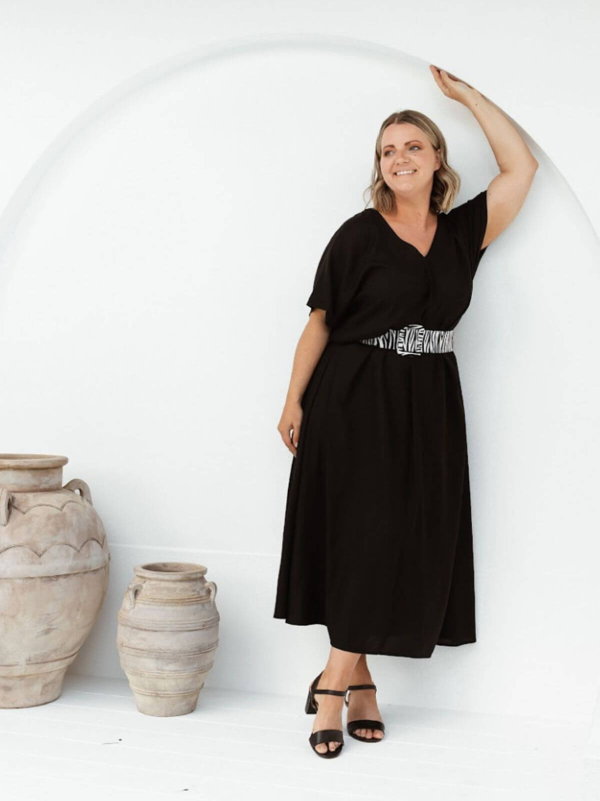 Mature model wearing black A-line maxi resort dress styled with zebra belt