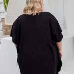 Close-up back view of a black kaftan top on a plus size model, showing fabric drape in size 2XL