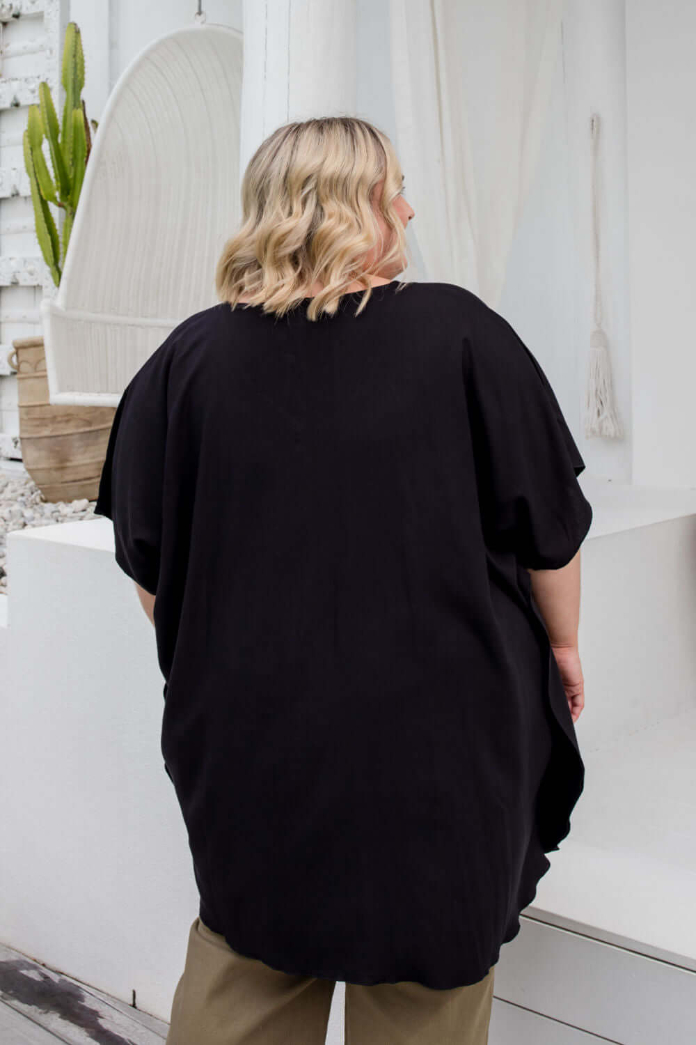 Close-up back view of a black kaftan top on a plus size model, showing fabric drape in size 2XL