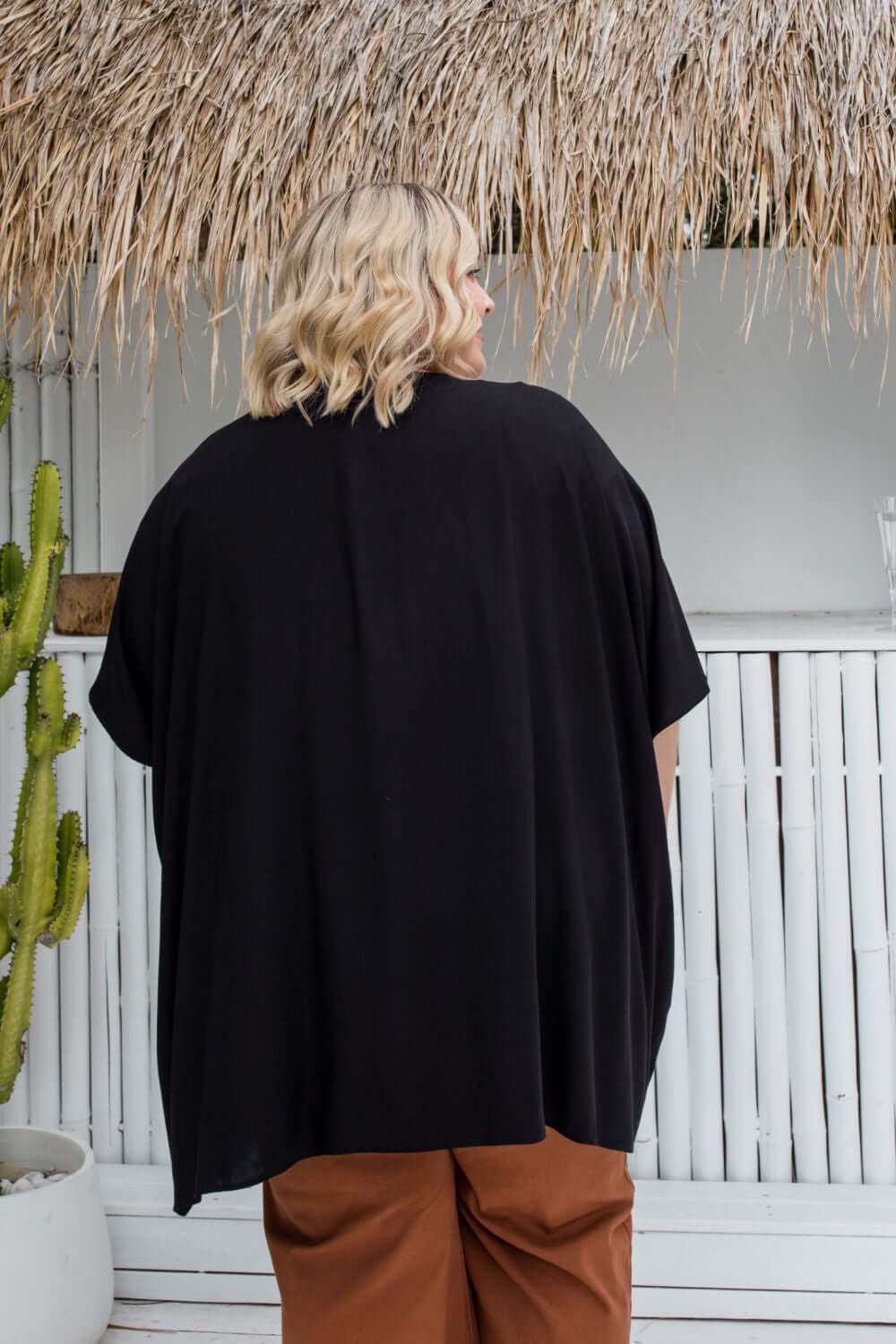 Back view of black kimono cape showing below-hip length on plus size woman