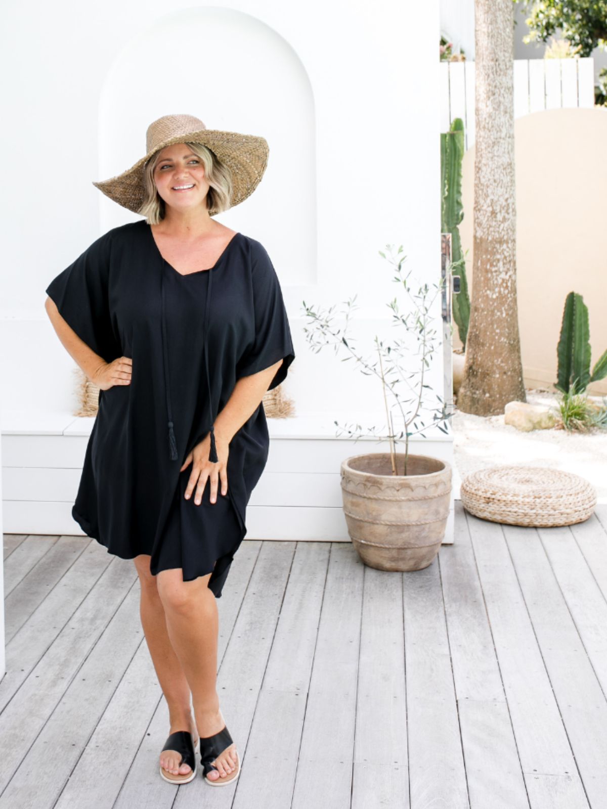 Model wearing short black kaftan and bamboo hat poolside