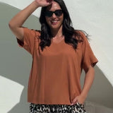 Woman wearing a mocha mousse brown top and relaxed fit leopard print pants poolside