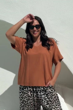 Woman wearing a mocha mousse brown top and relaxed fit leopard print pants poolside