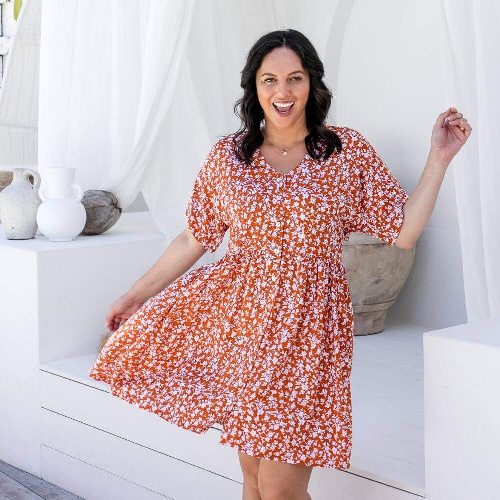 Mature model wearing burnt orange floral empire waist short resort dress with buttons