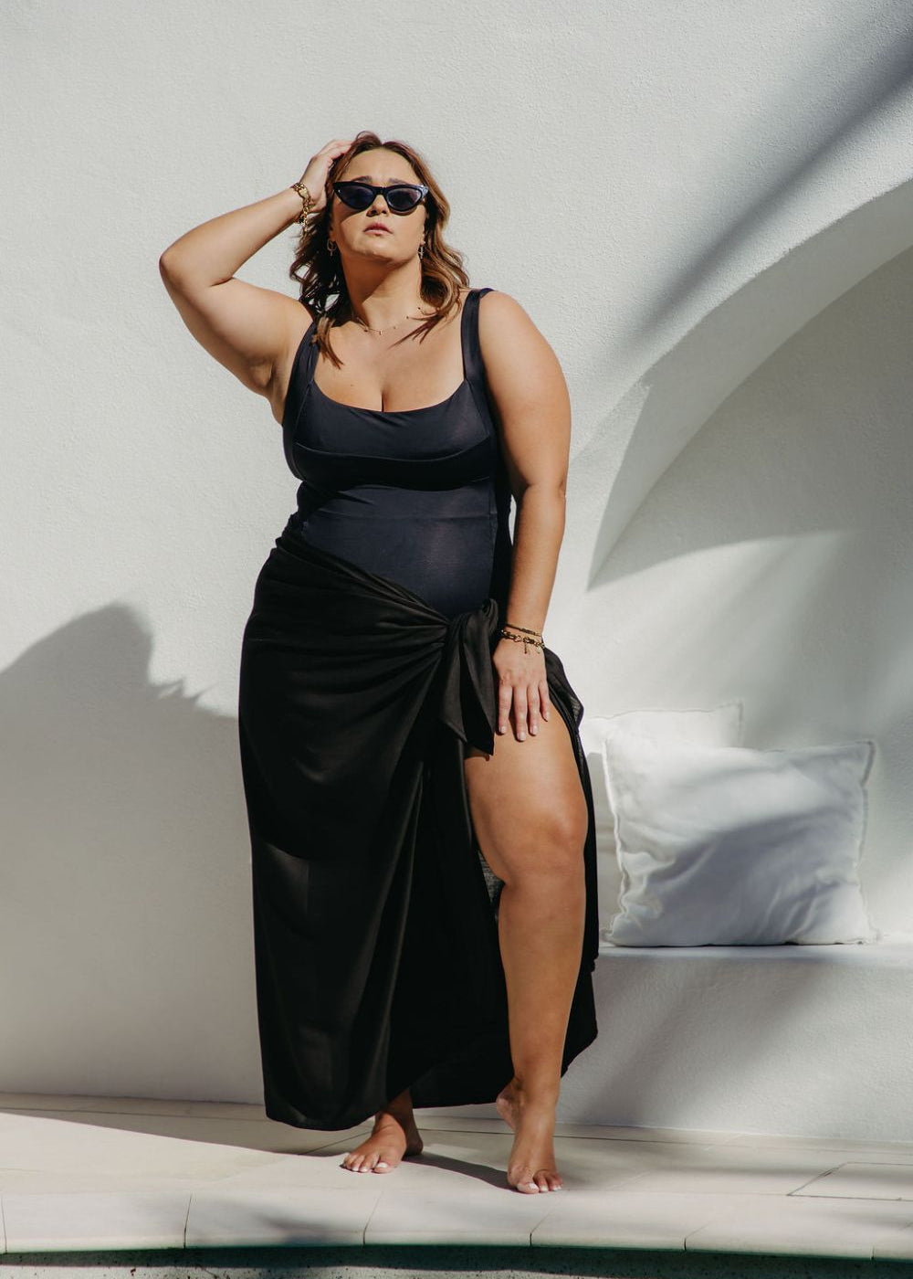 Woman in an extra large  black sarong standing by a poolside.