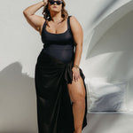 Woman in an extra large  black sarong standing by a poolside.