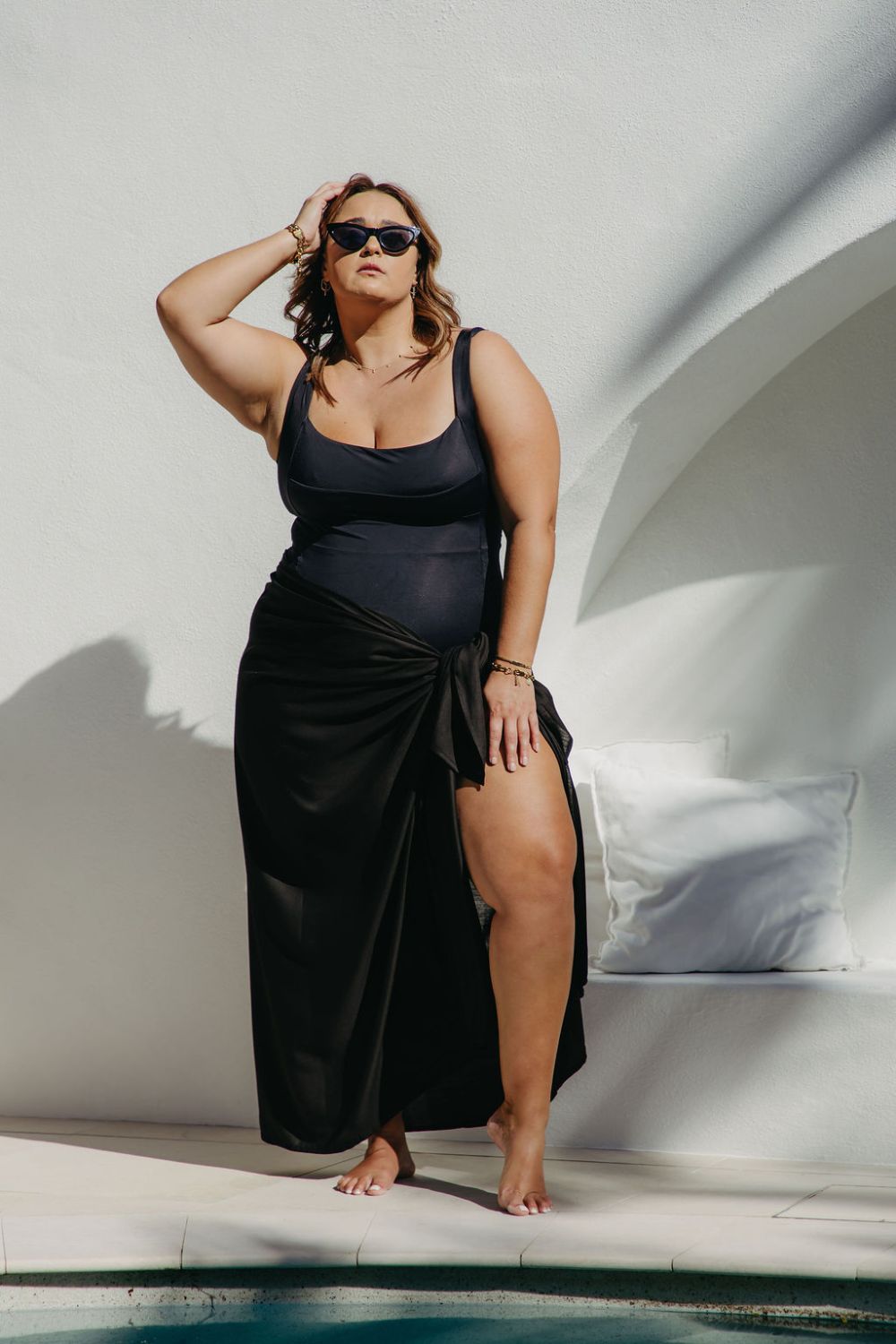 Woman in an extra large  black sarong standing by a poolside.