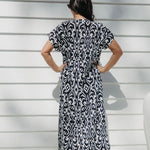 Lady wearing maxi summer dress in black and white pattern while  relaxing on the outdoor patio in filtered summer sun