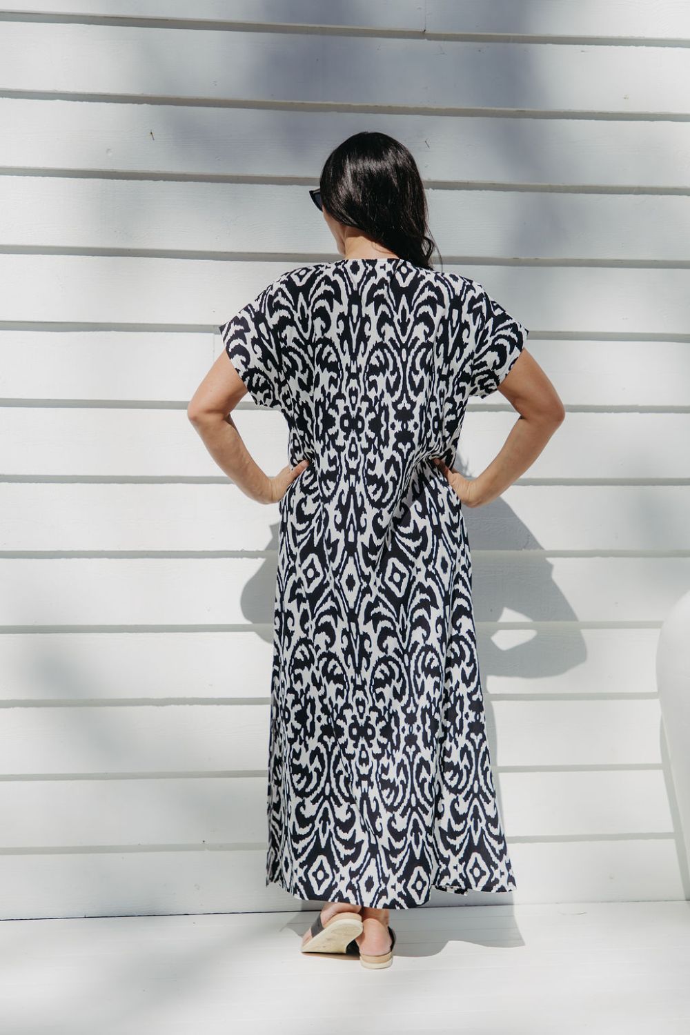 Lady wearing maxi summer dress in black and white pattern while  relaxing on the outdoor patio in filtered summer sun