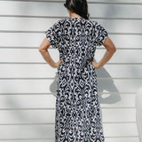 Lady wearing maxi summer dress in black and white pattern while  relaxing on the outdoor patio in filtered summer sun