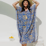 Woman wearing a blue and yellow Positano inspired print designed kaftan dress and straw hat in Italian seaside resort