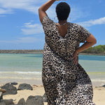Woman wearing a leopard print dress standing on a Sunshine Coast beach in Queensland with a blue sky and ocean in the background.