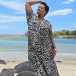 Woman in a leopard print dress standing on a Sunshine Coast beach with blue sky and water in the background