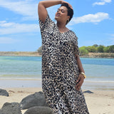 Woman in a leopard print dress standing on a Sunshine Coast beach with blue sky and water in the background