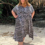 Woman in a leopard print dress and hat standing on a sandy beach at the Gold Coast Australia