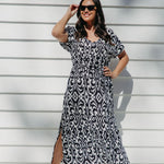 Woman wearing a black and white geometric print maxi dress on outdoor patio on a summer day