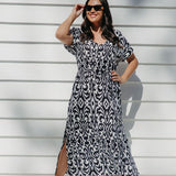 Woman wearing a black and white geometric print maxi dress on outdoor patio on a summer day