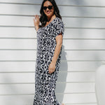 Lady wearing long summer dress in black and white geometric print relaxing on the outdoor patio in filtered summer sun