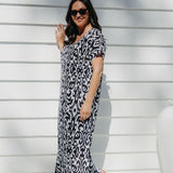 Lady wearing long summer dress in black and white geometric print relaxing on the outdoor patio in filtered summer sun
