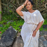 Lady in a white and beige leopard print long summer dress standing among rocks and greenery at the Sunshine Coast