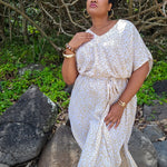 Woman in a beige and white maxi dress in leopard print standing at the beach