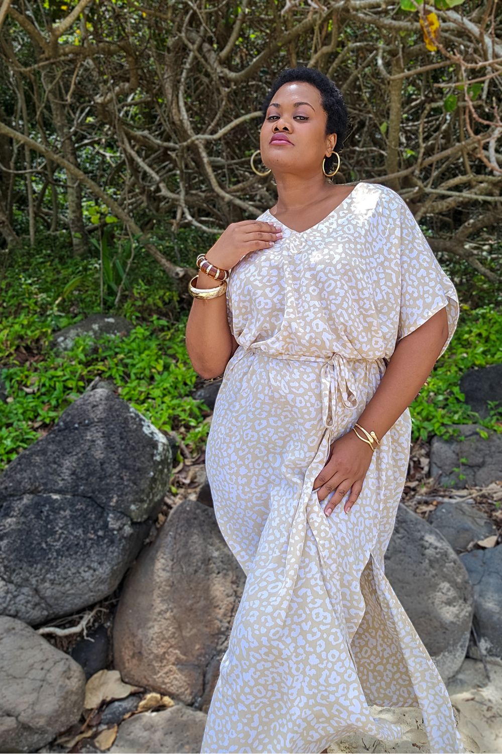 Woman in a beige and white maxi dress in leopard print standing at the beach