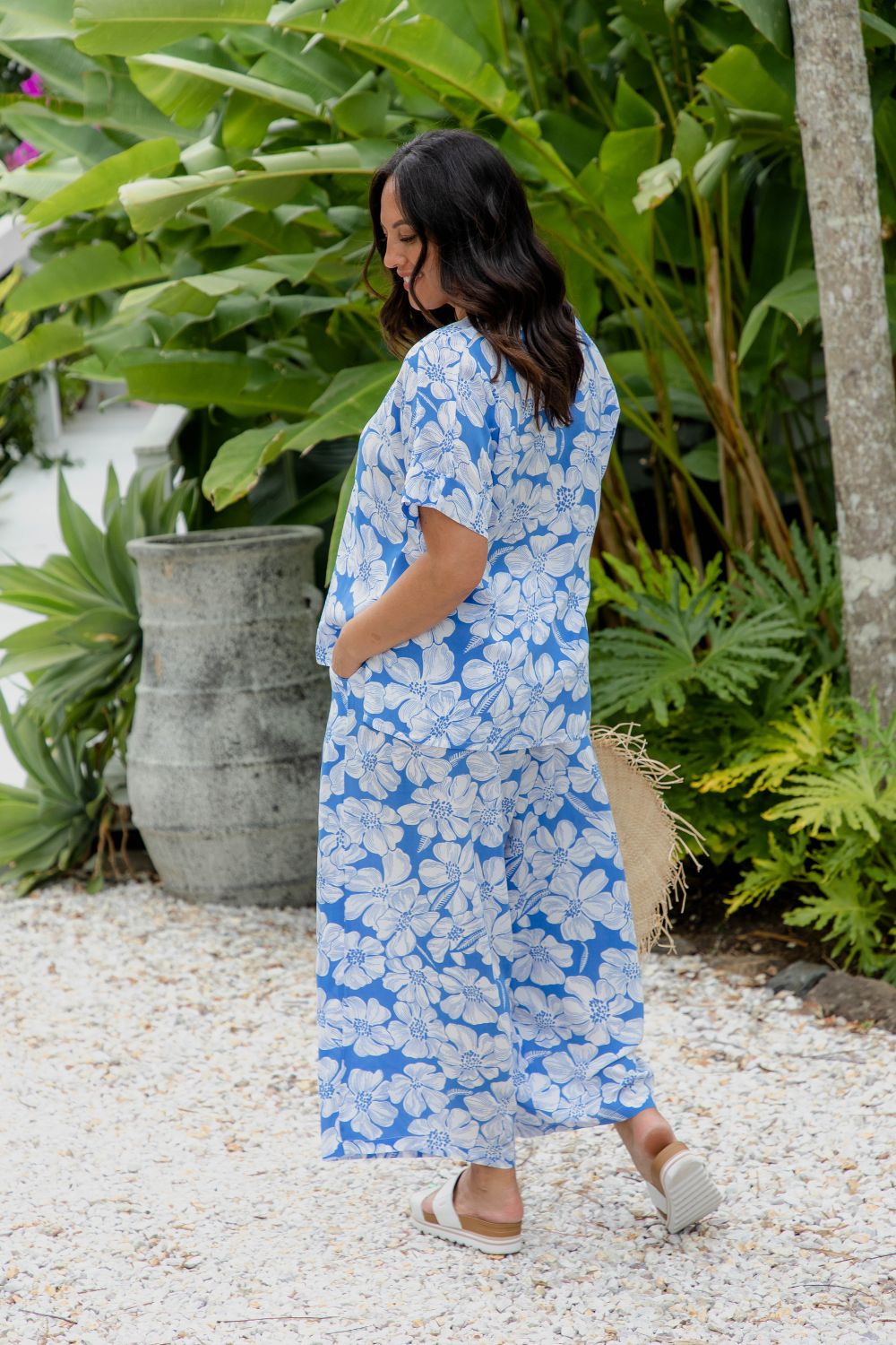 outfit-set-Palazzo-pants-with-matching-summer-top-in-blue-white-hibiscus-floral being worn by lady in tropical garden