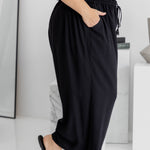 Side view of black Palazzo Pants with knee bent – showing wide-leg cut and functional pocket
