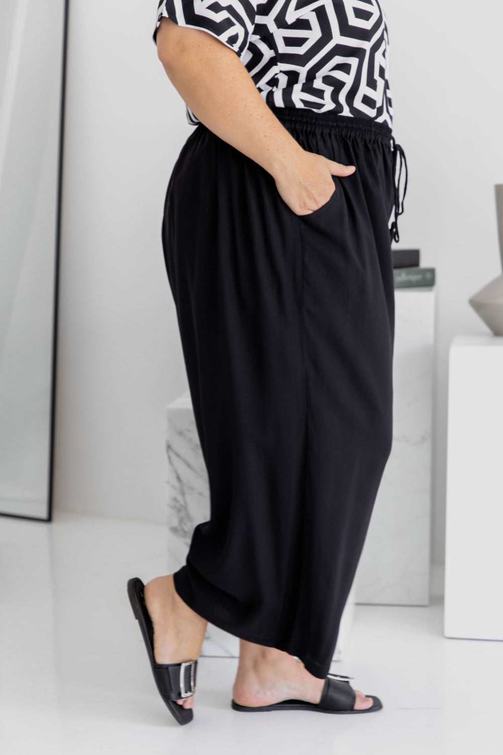 Side view of black Palazzo Pants with knee bent – showing wide-leg cut and functional pocket