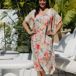 Mature model wearing size small Springtime Kaftan with bold floral print and orange wedges, standing on tropical deck – summer chic resort outfit