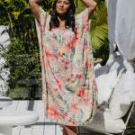 Model wearing size small Springtime Kaftan with arms raised, displaying wide kimono sleeves and bold floral print – standing on summer deck
